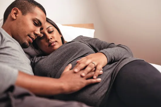 photo of young african pregnant couple in bed